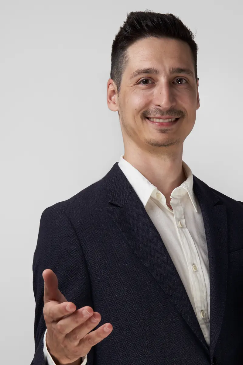 Andrei smiling, reaching one open hand toward the camera.
