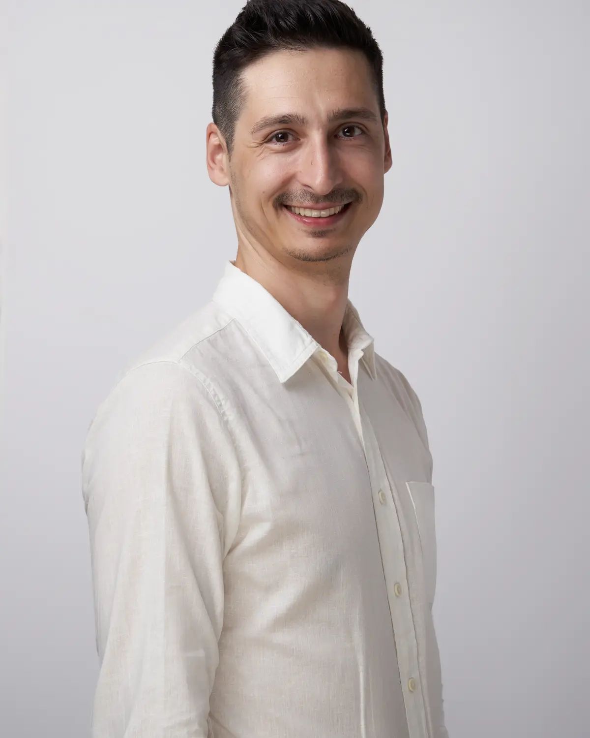 Andrei Panainte, smiling, in a white shirt against a light grey background.